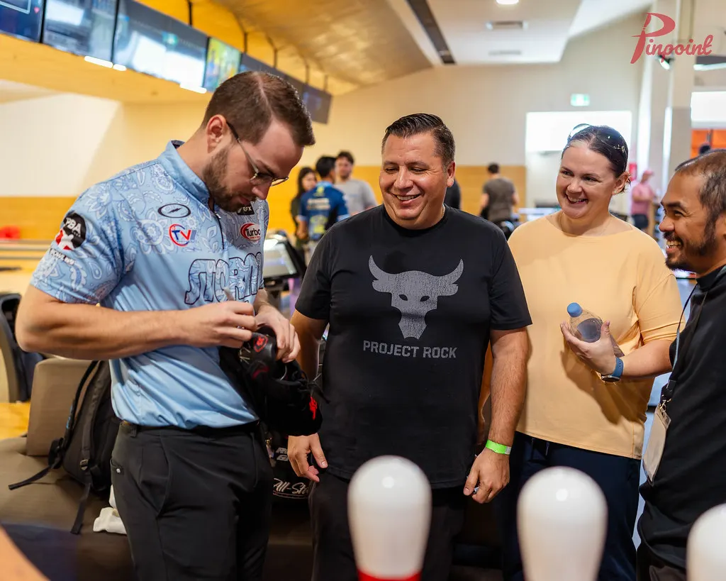 Chris Via signs a ball while bowlers laugh at our first clinic, 2024